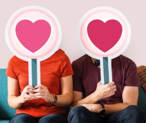 A picture of man and women holding puck card of heart shape